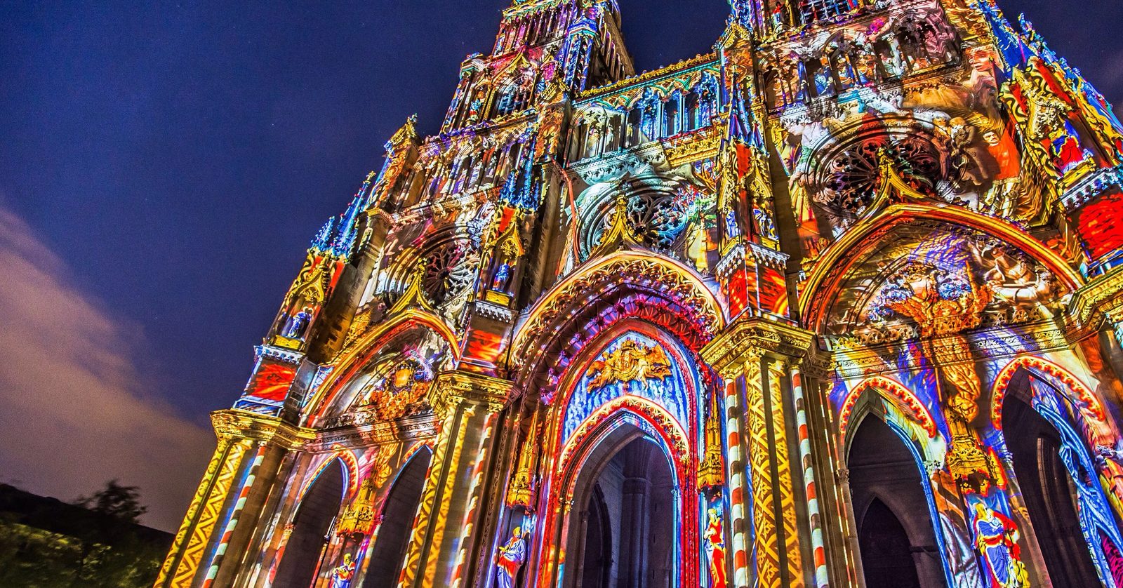 Fachada histórica coberta por projeção de luz colorida à noite