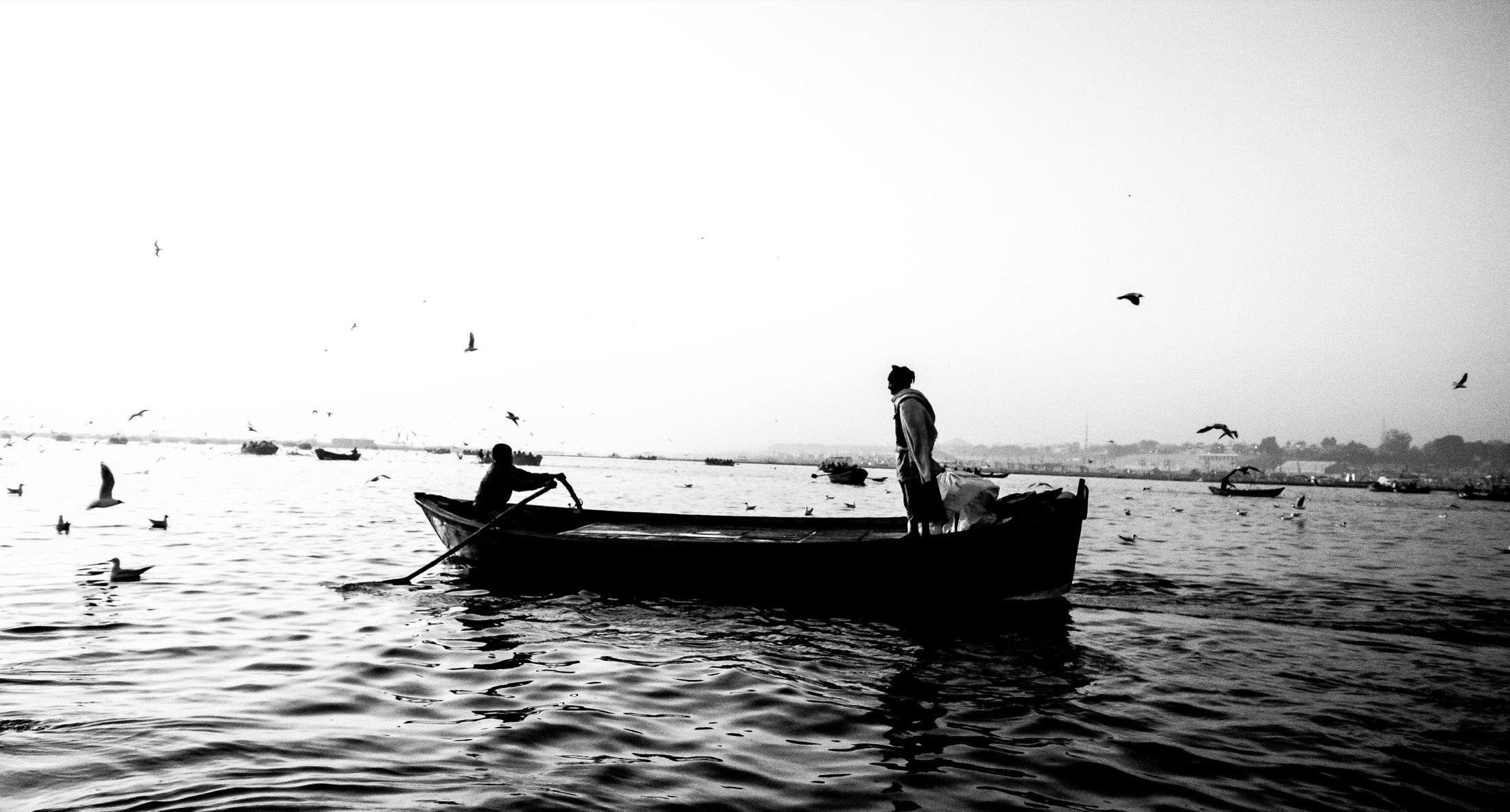 O rio antes do amanhecer, um barco atravessando devagar, em preto e branco